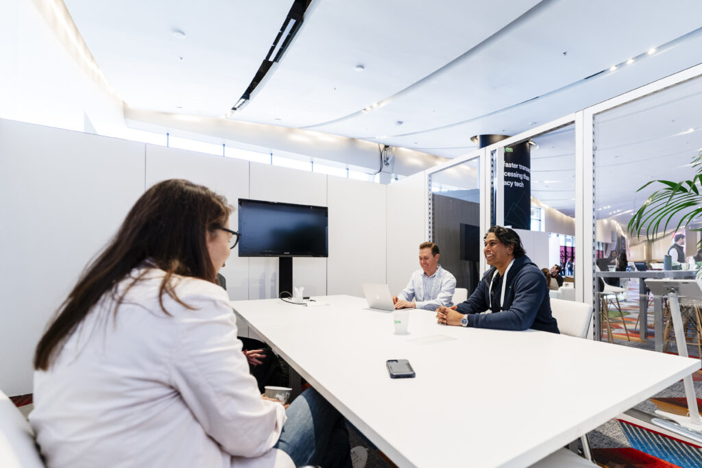 Executives in a breakout meeting with event attendees inside a private meeting room at a corporate trade show lounge.