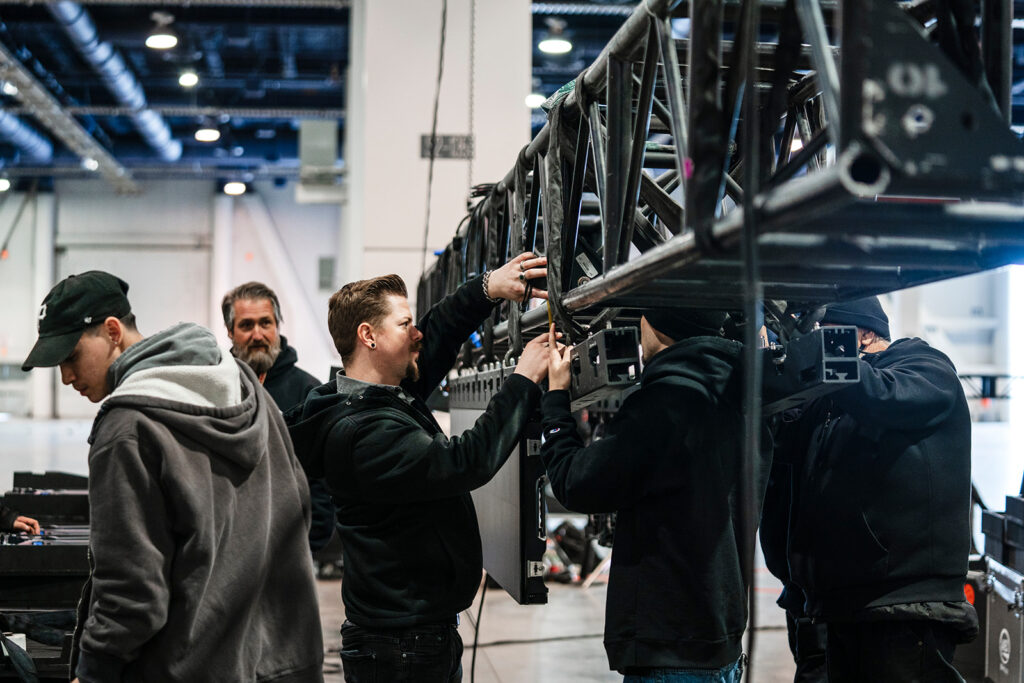 Event production crew assembling a large LED video wall, showcasing behind-the-scenes setup at a trade show.