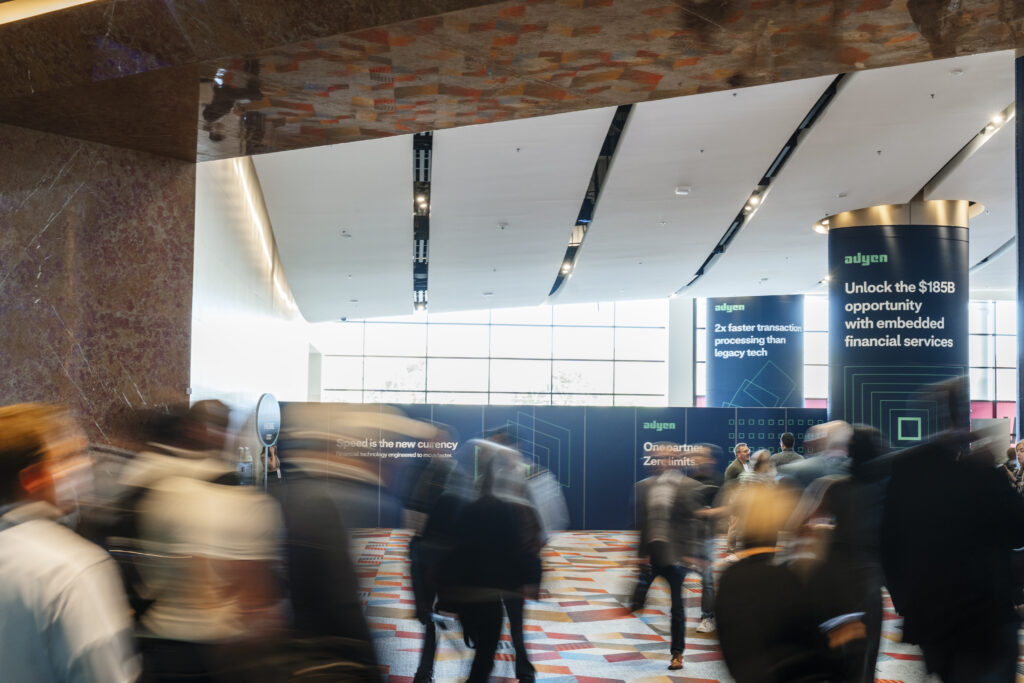 Attendees moving through the Sands Expo lobby with branded exhibitor advertising displayed on the walls, captured during a Las Vegas convention