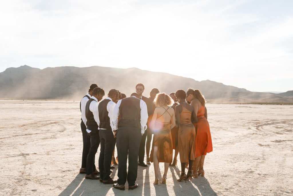Groom praying with wedding party before the ceremony at a Vegas Dry Lake Bed