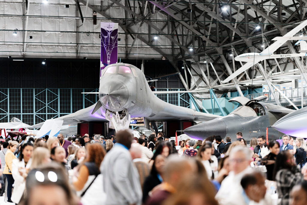 Attendees mingling during a corporate reception hosted in a Denver airplane hangar, captured by a corporate event photographer