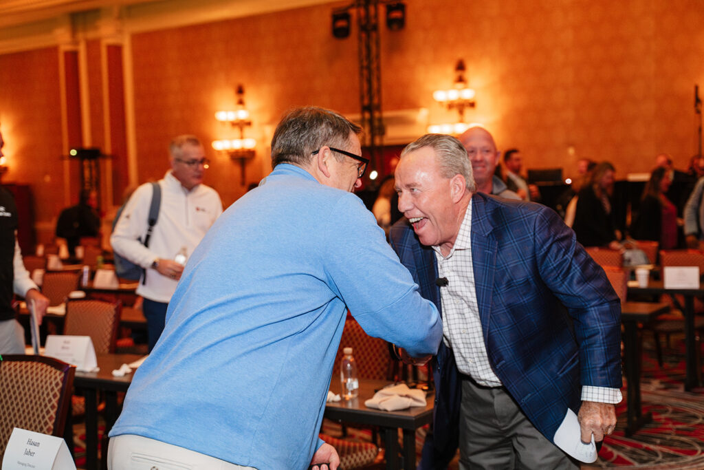 Association event photography captures two association members greeting each other during a conference session, an authentic moment of connection and engagement.