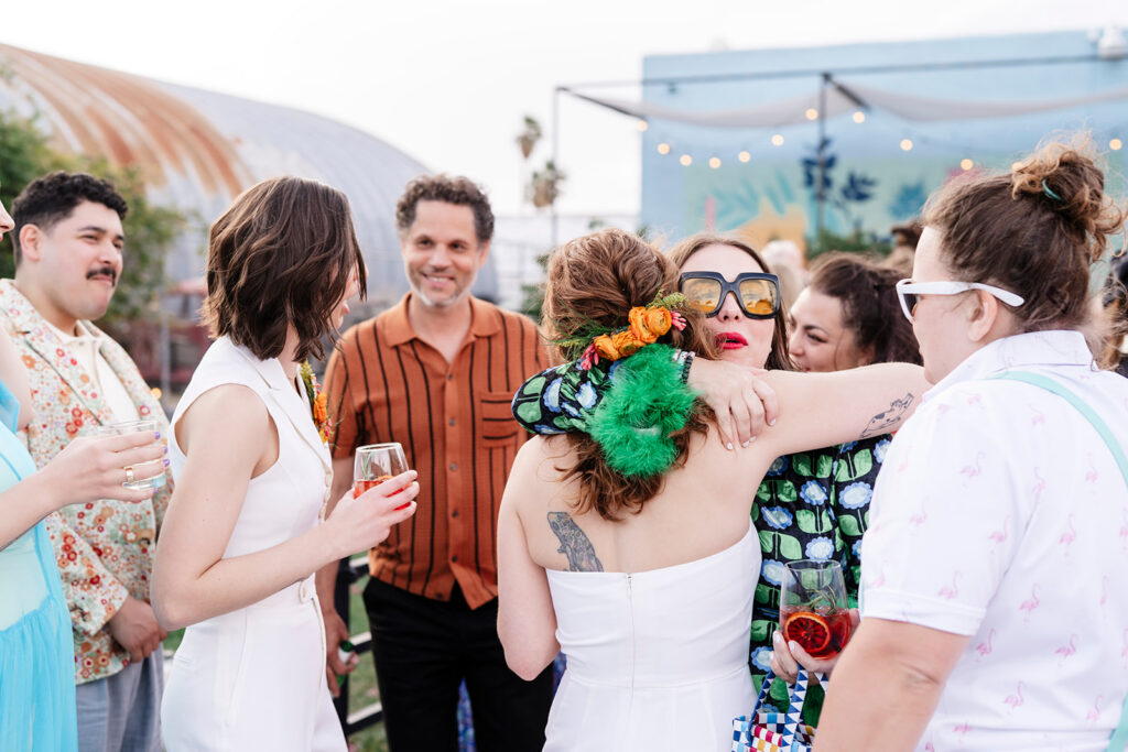 Brides giving hugs to their friends during cocktail hour at their large scale wedding