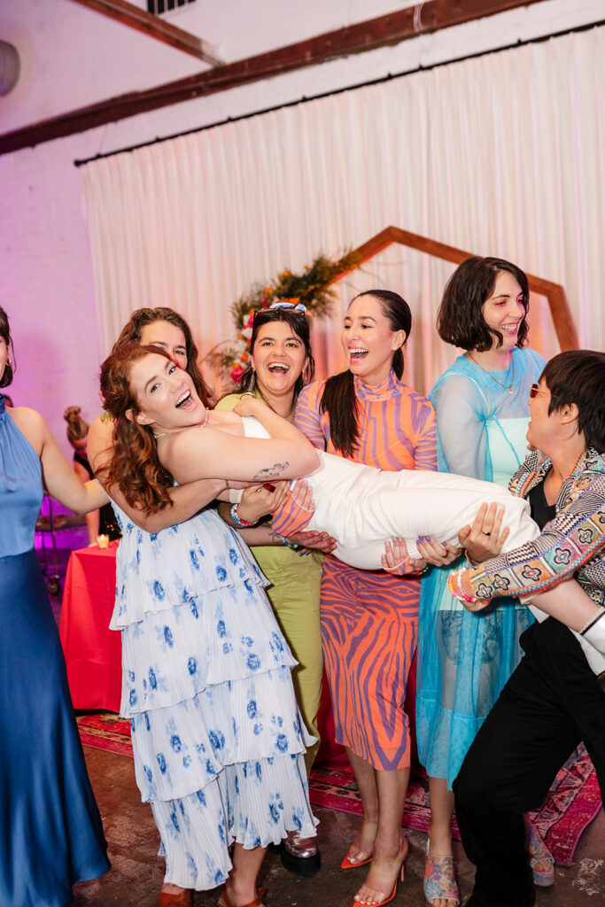 Bride celebrating with friends at her wedding reception, illustrating the high-energy, community-focused experience of a traditional wedding.