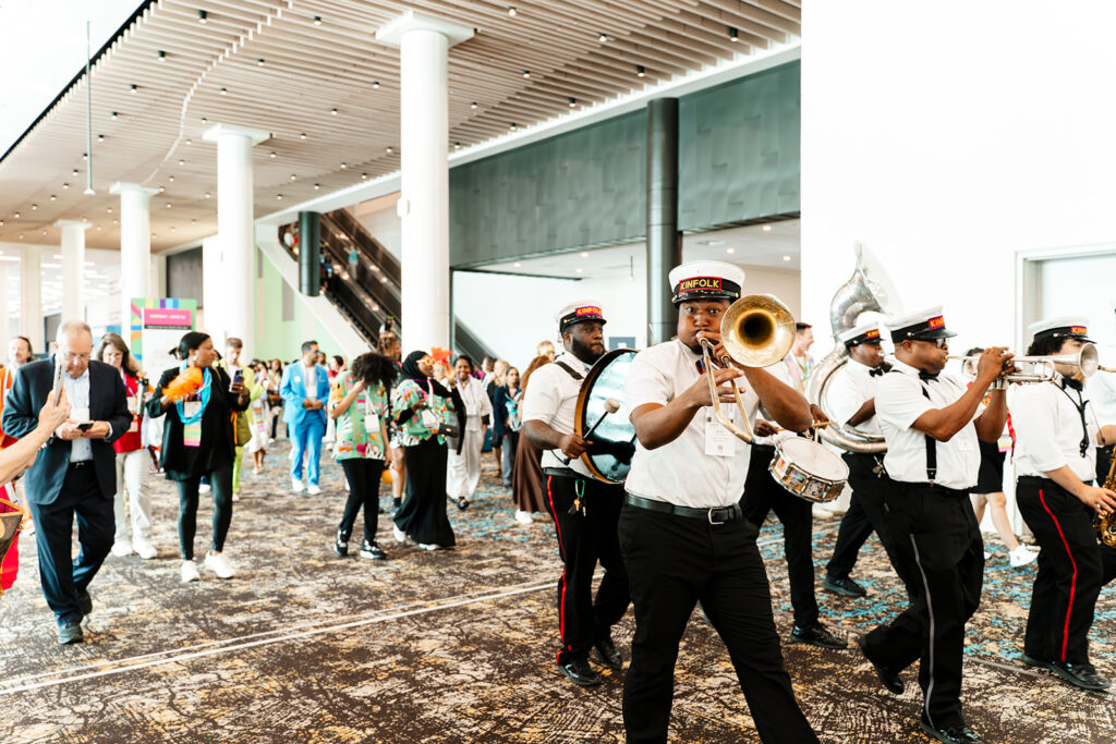 Event photography captures A live brass band leads attendees through a conference space in Las Vegas, capturing the energy, scale, and experiential atmosphere of a large corporate event.
