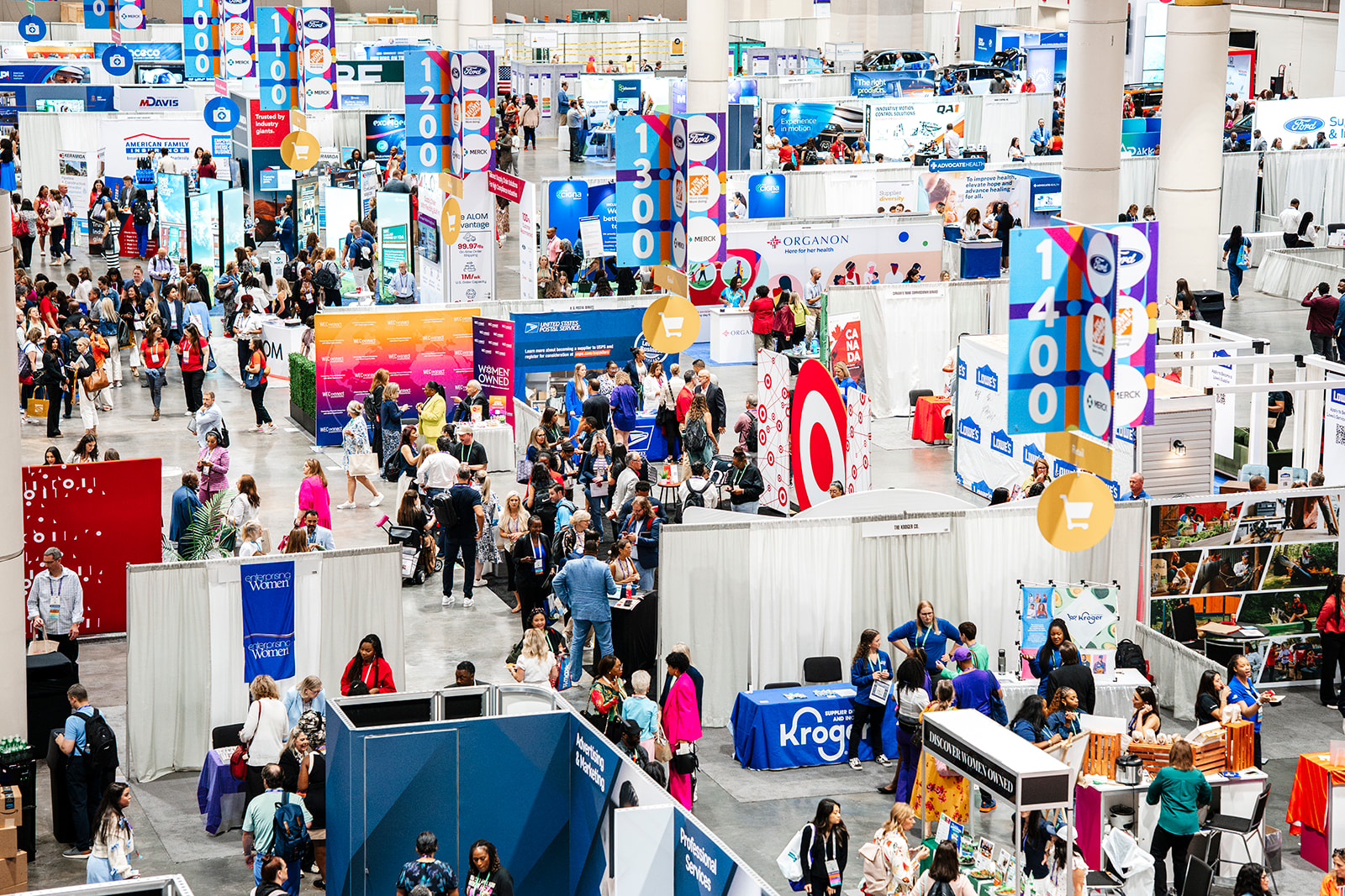 Attendees on a busy trade show floor in an exhibit hall.