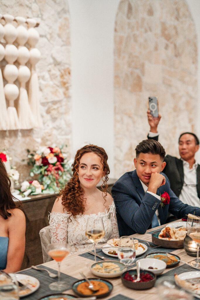 Bride and groom seated at a Las Vegas intimate wedding reception dinner, smiling during heartfelt toasts at a modern restaurant venue.