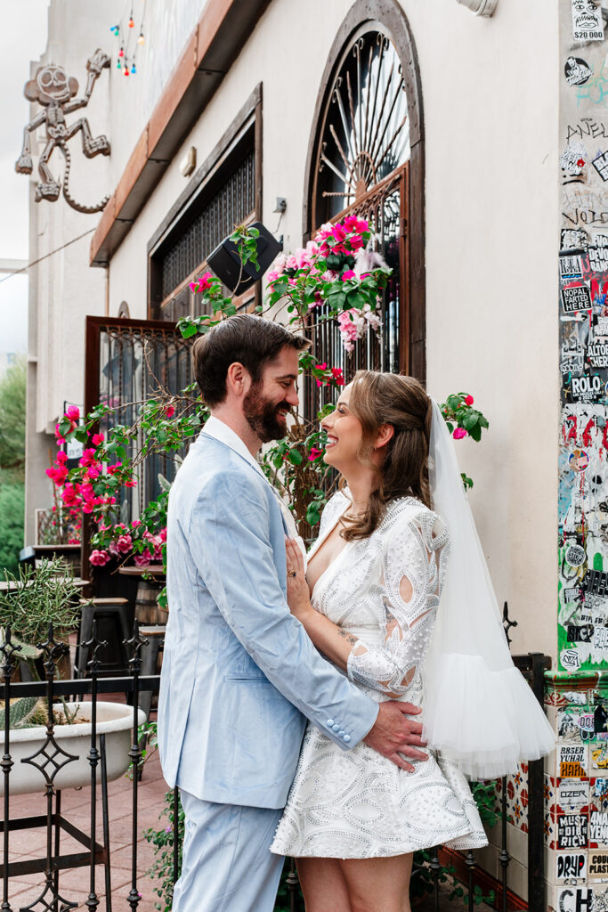 Couple laughing together outside colorful Arts District building with bougainvillea — Las Vegas elopement photography by True Colors Creative