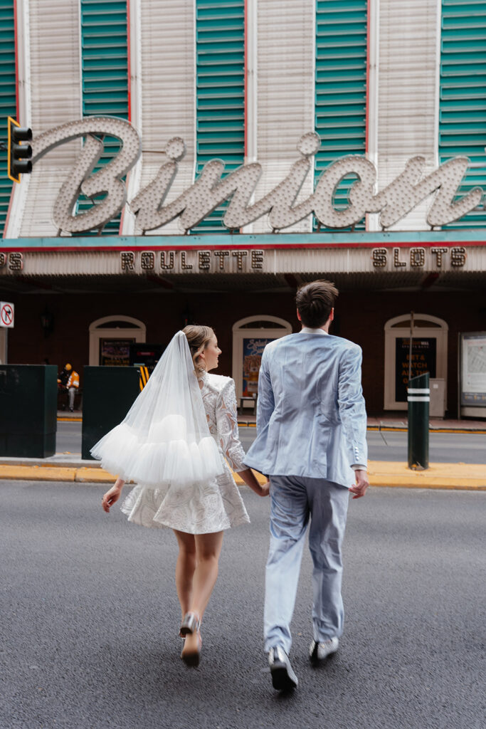 Newly married couple walking beneath the vintage Binion’s sign in downtown Las Vegas after a private elopement ceremony, showcasing how elopements allow for experience-driven portraits and destination storytelling.