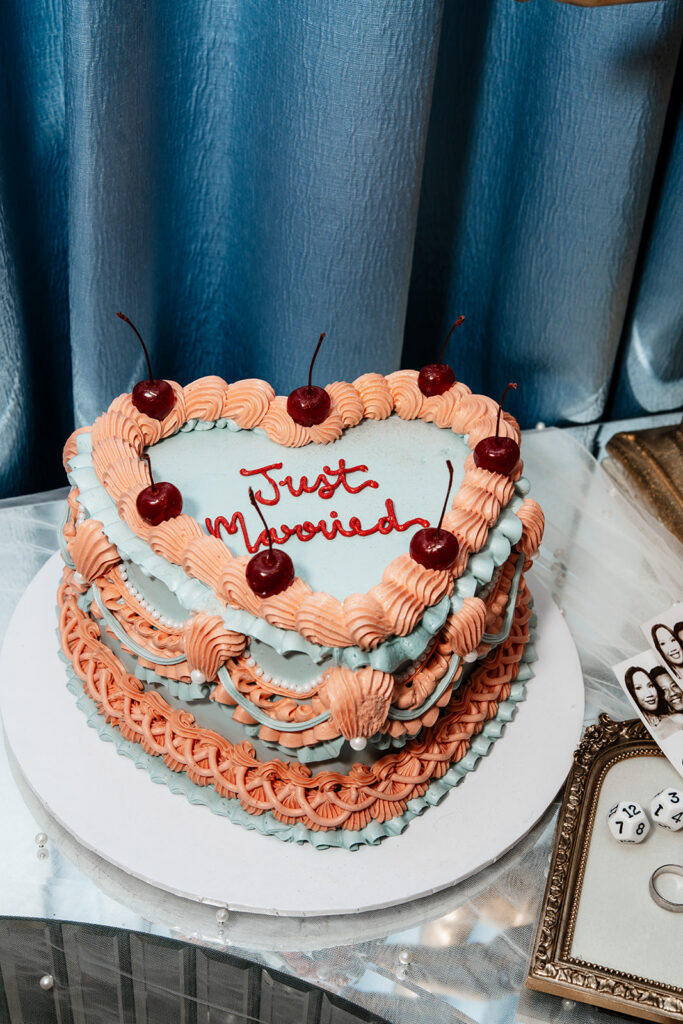 Heart-shaped “Just Married” wedding cake with piped detailing and cherries, capturing the celebratory reception moments that define many traditional weddings