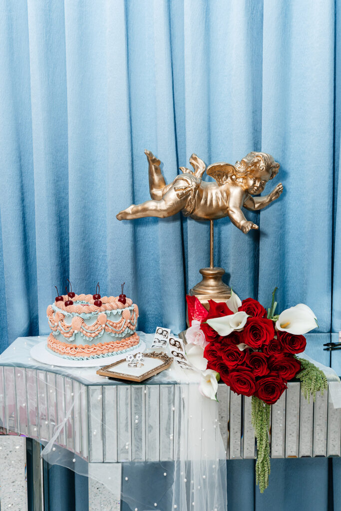 Wedding reception detail with heart-shaped cake, red rose bouquet, and decorative accents, highlighting the layered design and personalization of a full wedding celebration.