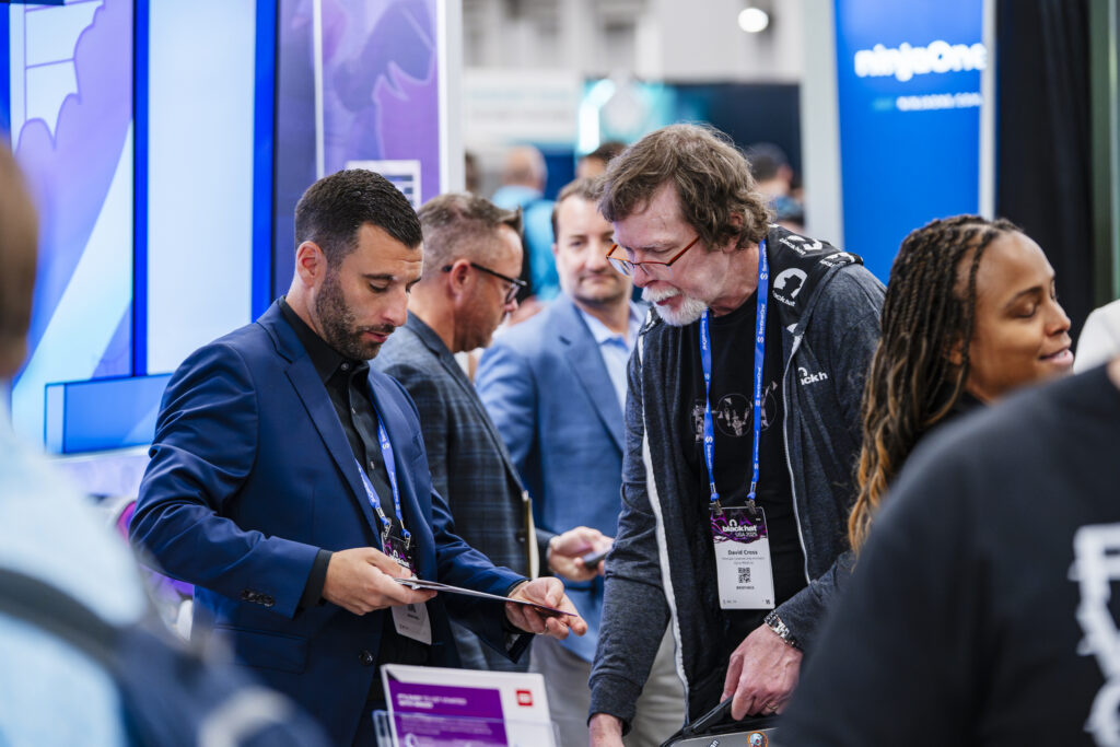Exhibit photography capturing attendee interaction in a booth during a product demo.