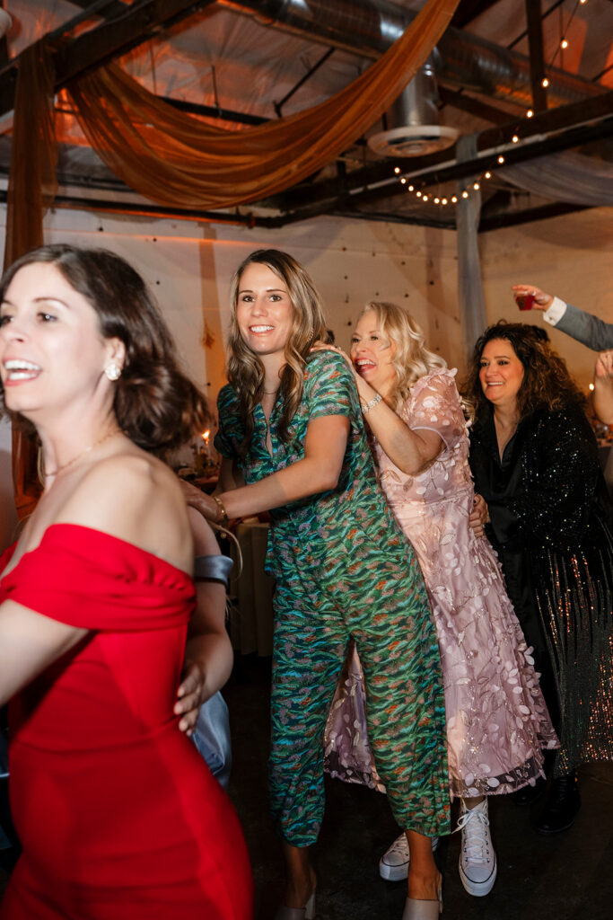 Wedding guests dancing and celebrating on a lively reception dance floor at a large scale wedding captured by True Colors Team destination wedding photographers