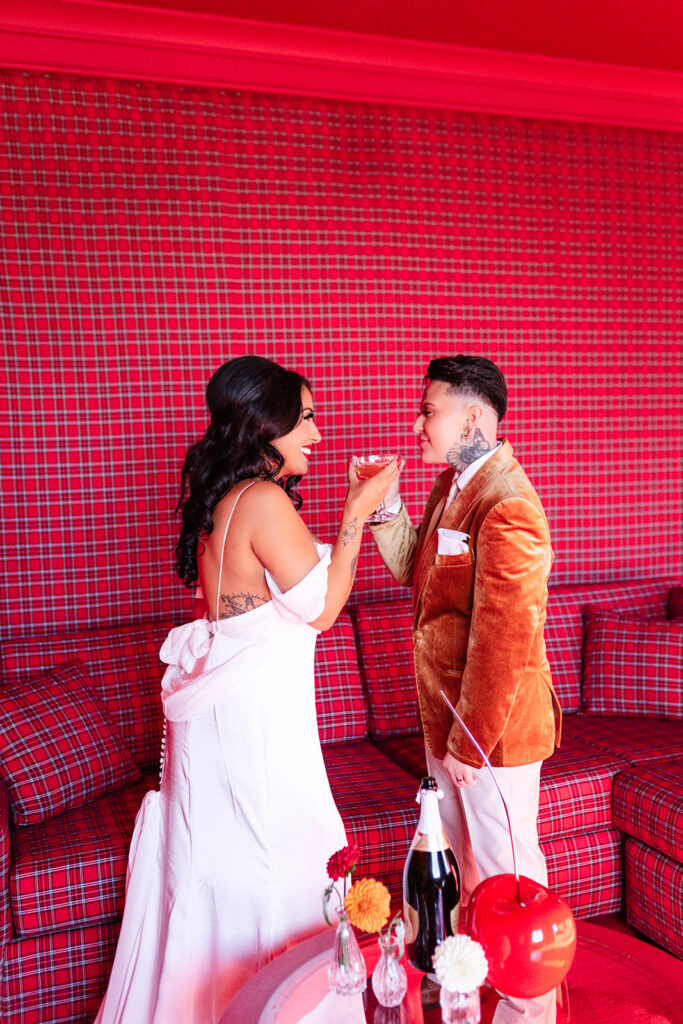 Newlyweds toasting champagne in a red plaid private suite during an intimate Las Vegas elopement at Westgate.