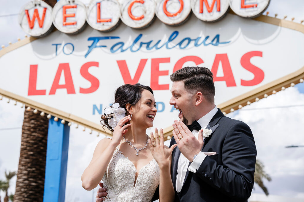 Elopement photographer documenting newlyweds celebrating with wedding rings at the Welcome to Fabulous Las Vegas sign.
