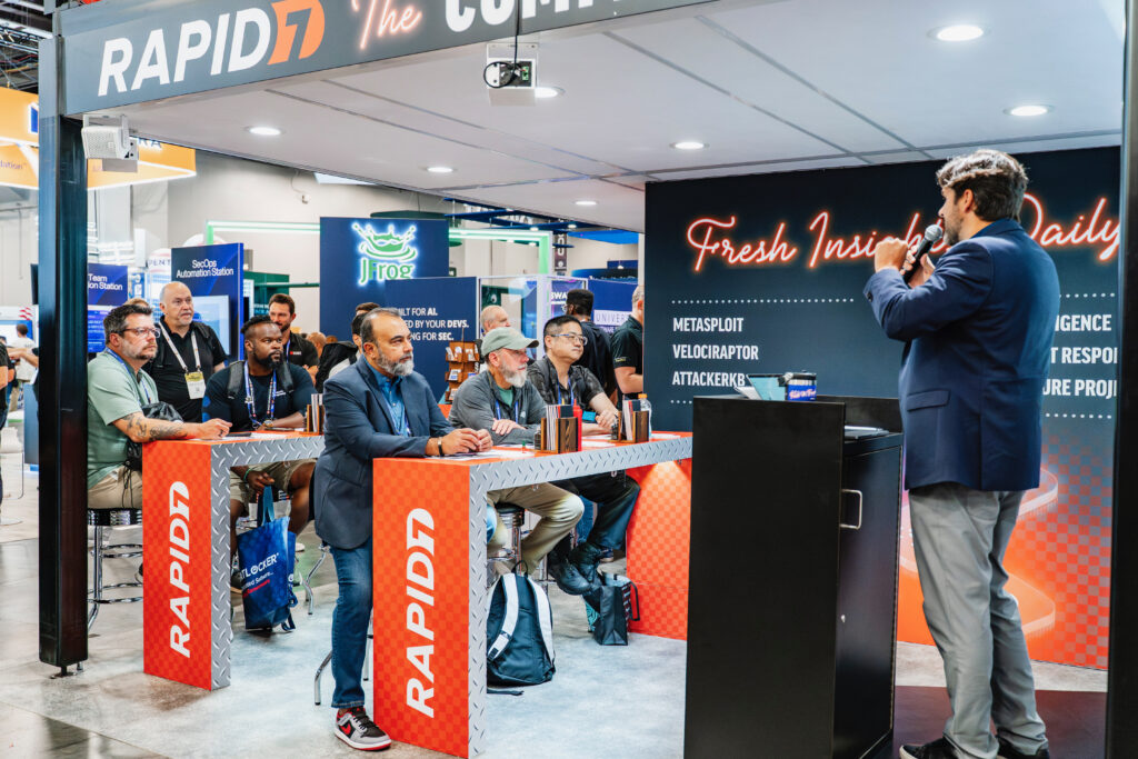 Exhibit photography capturing attendees in a booth engage with with an exhibitor during a presentation.