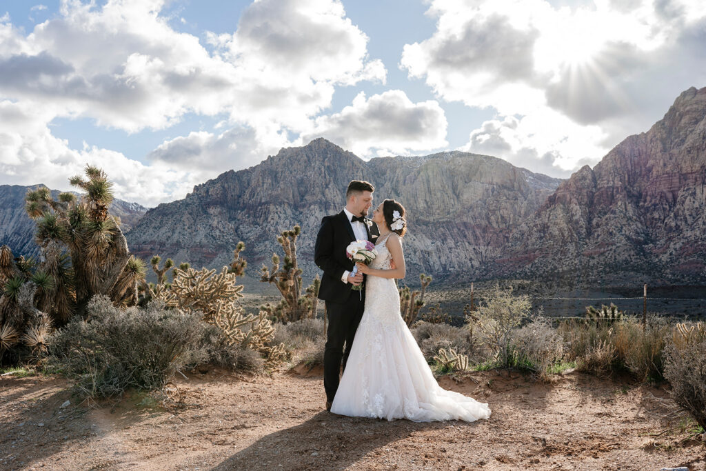 Elopement photographer capturing romantic portrait of bride and groom at Red Rock Canyon with dramatic mountain backdrop.